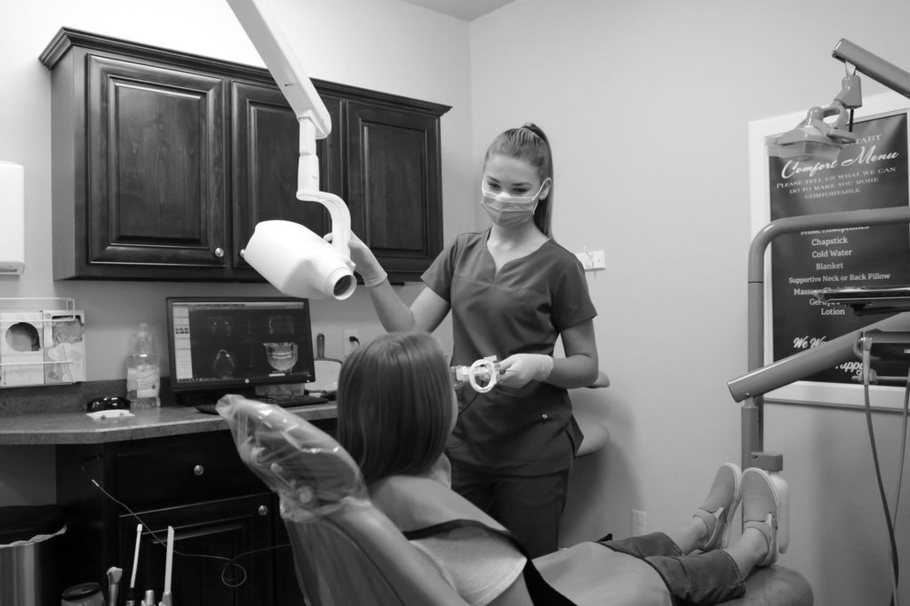 dental assistant talking to a patient in dental chair before taking a dental xray