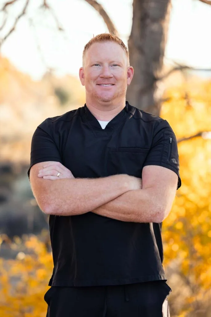 The image shows a photo of Dr. hull wearing a black scrubs while crossing his arms, the background is outdoor.